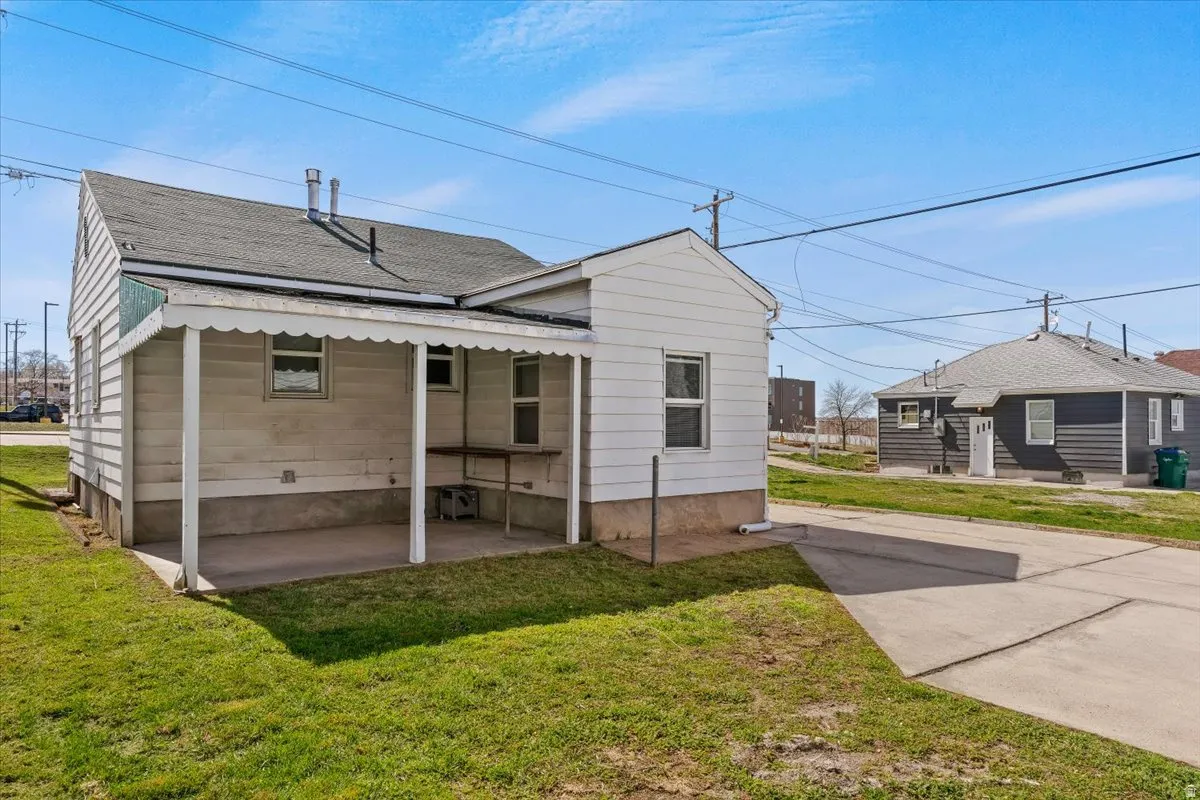 Back of property with a yard and roof with shingles