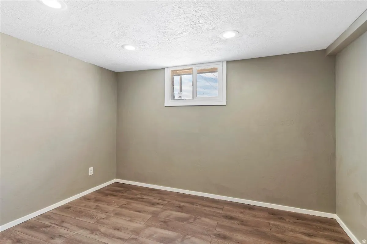 Empty room featuring wood finished floors, recessed lighting, and a textured ceiling
