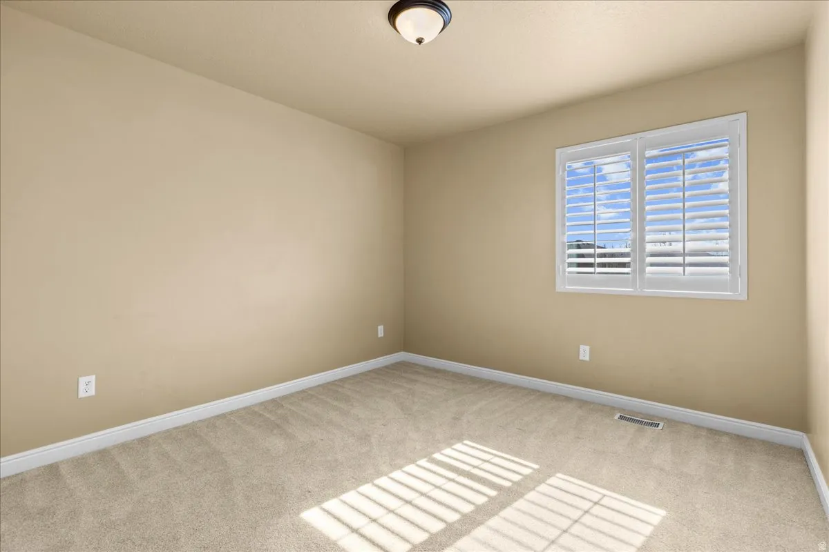 Spare room with baseboards and light colored carpet