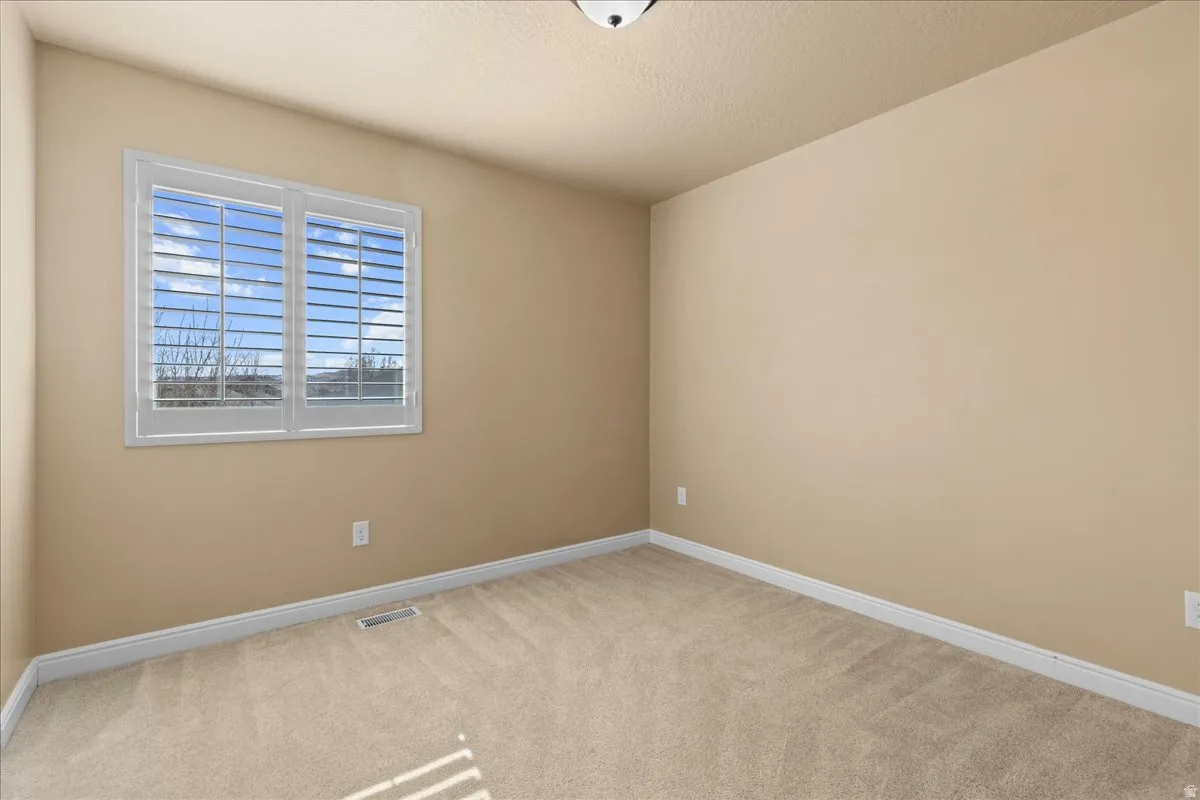 Spare room featuring light carpet and a textured ceiling
