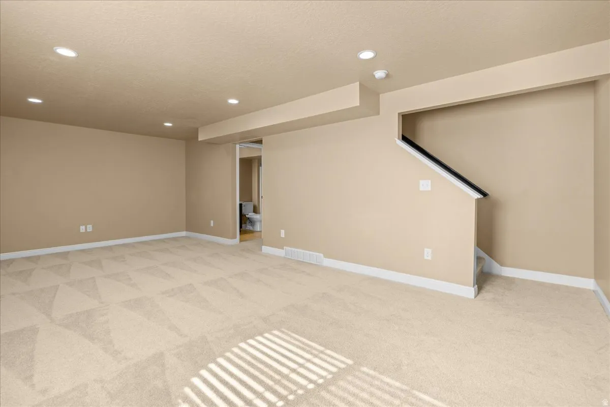 Finished basement with light carpet, recessed lighting, and a textured ceiling
