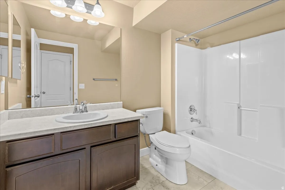 Bathroom featuring vanity, shower / bathtub combination, and light tile patterned flooring