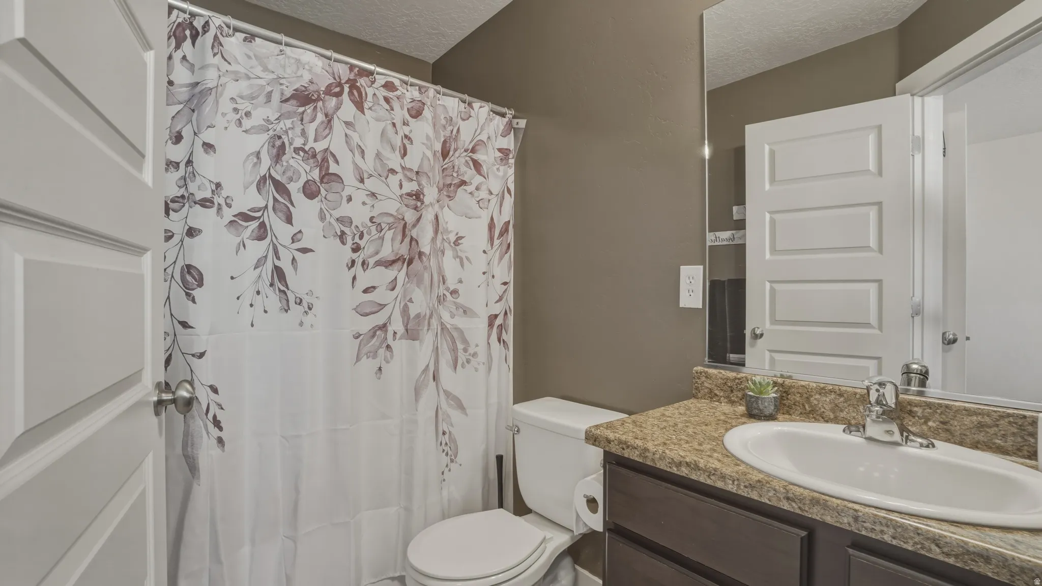 Bathroom with vanity, a shower with shower curtain, and a textured ceiling