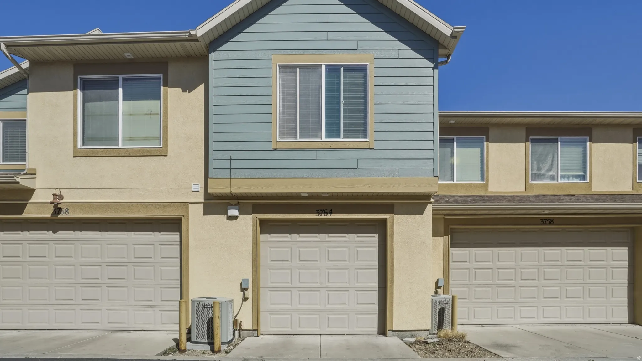 View of front of property with stucco siding, an attached garage, and driveway