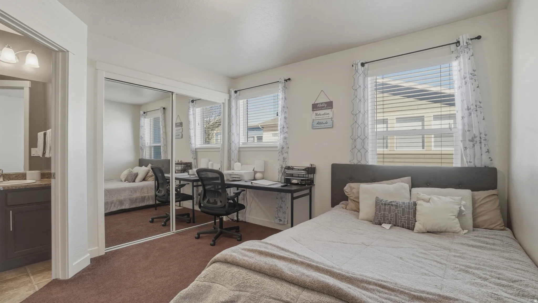 Bedroom featuring an office area, dark colored carpet, a closet, and ensuite bath