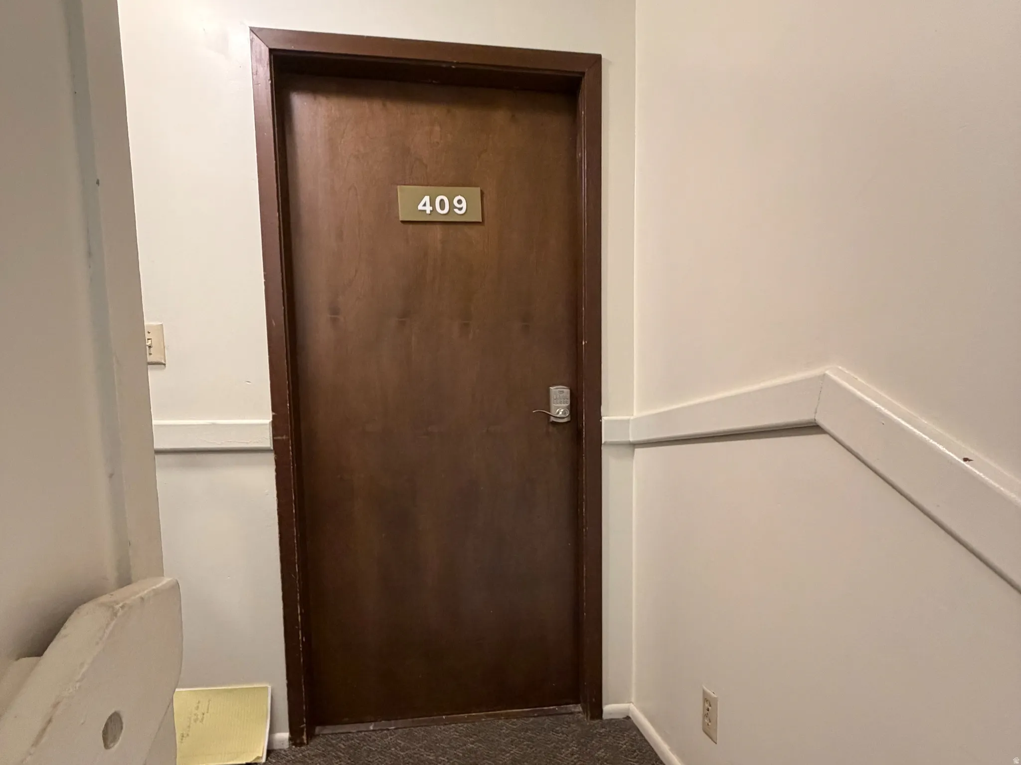 Corridor featuring dark carpet and baseboards