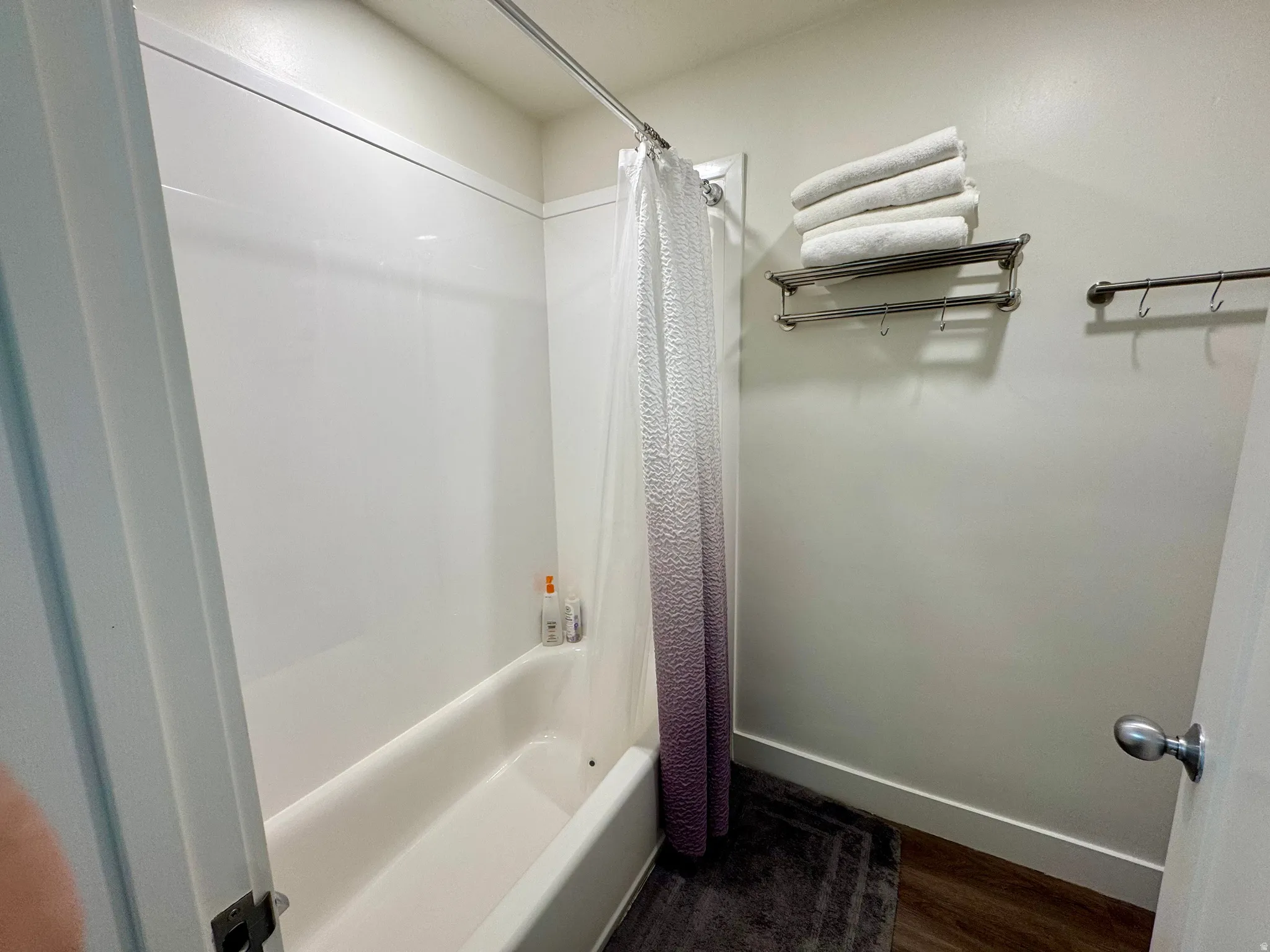 Bathroom with shower / bath combination with curtain and dark wood-type flooring