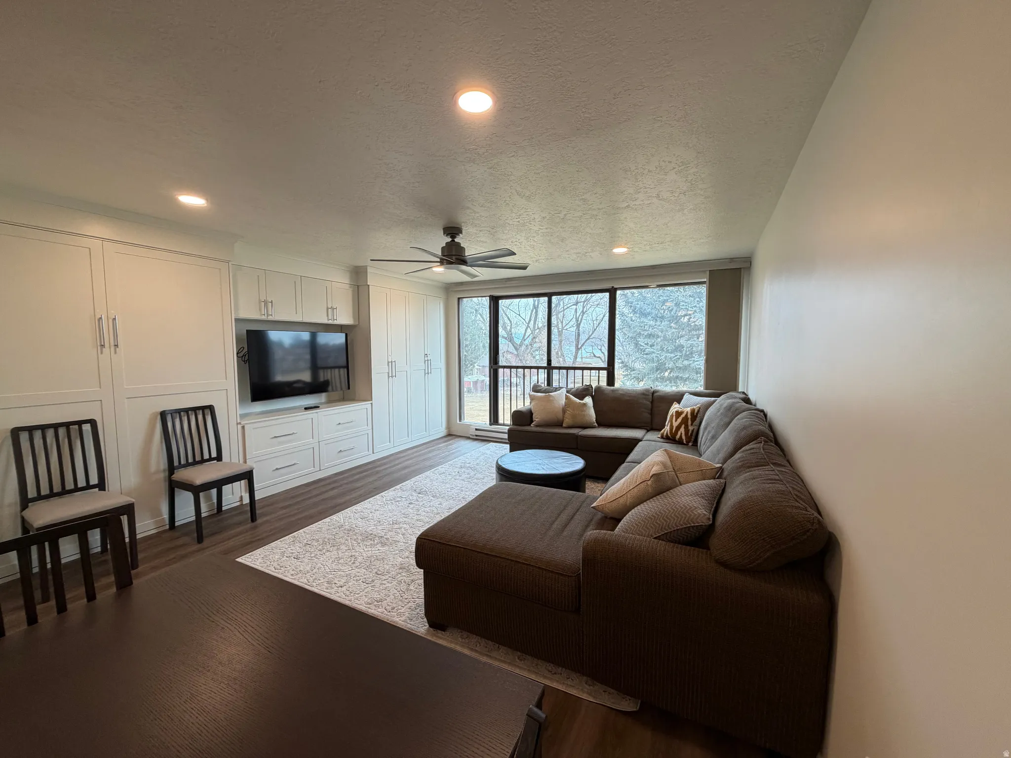 Living area featuring a textured ceiling, recessed lighting, ceiling fan, and dark wood-style flooring