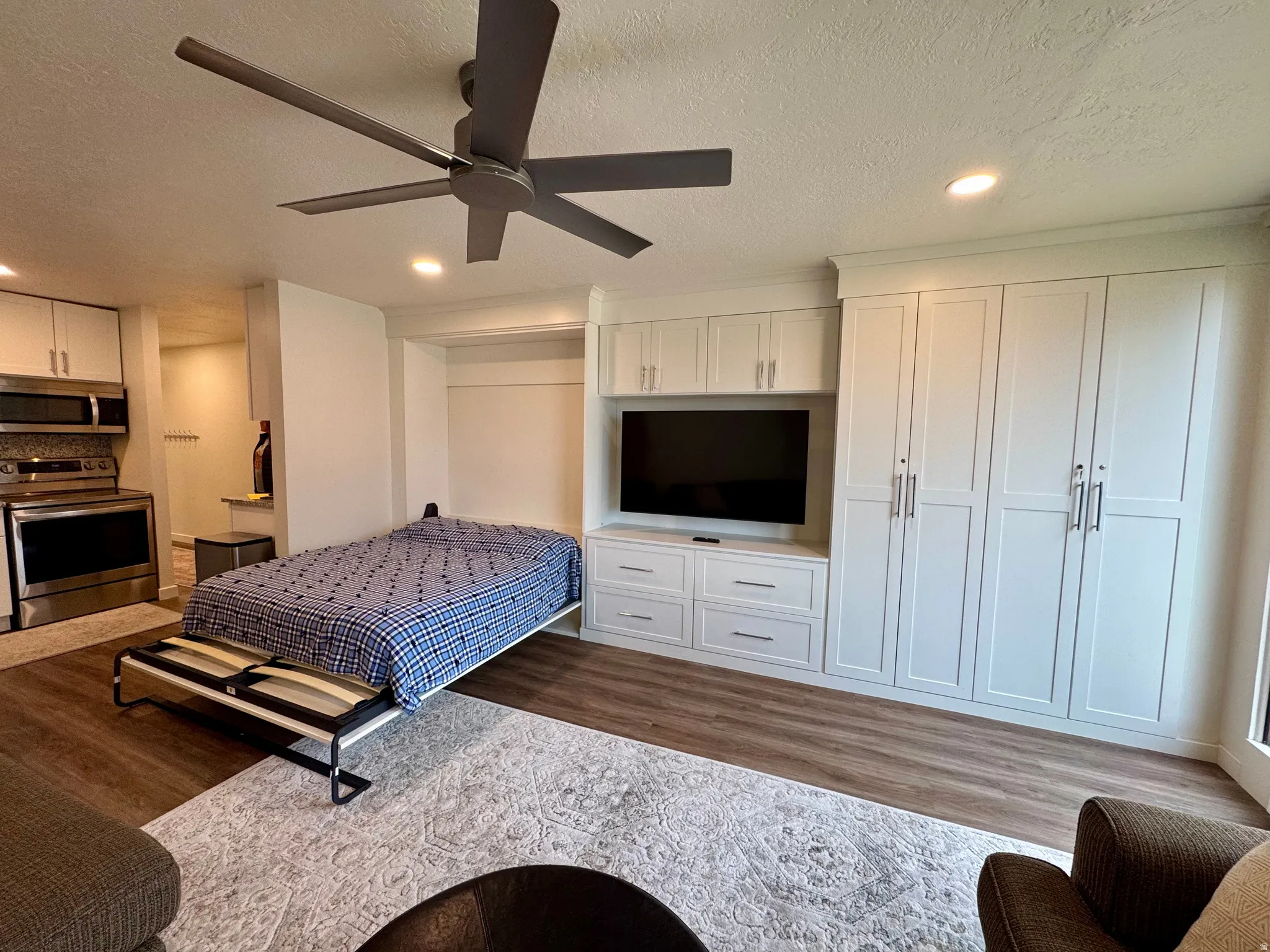 Bedroom with light wood-style flooring, a textured ceiling, recessed lighting, a ceiling fan, and two closets