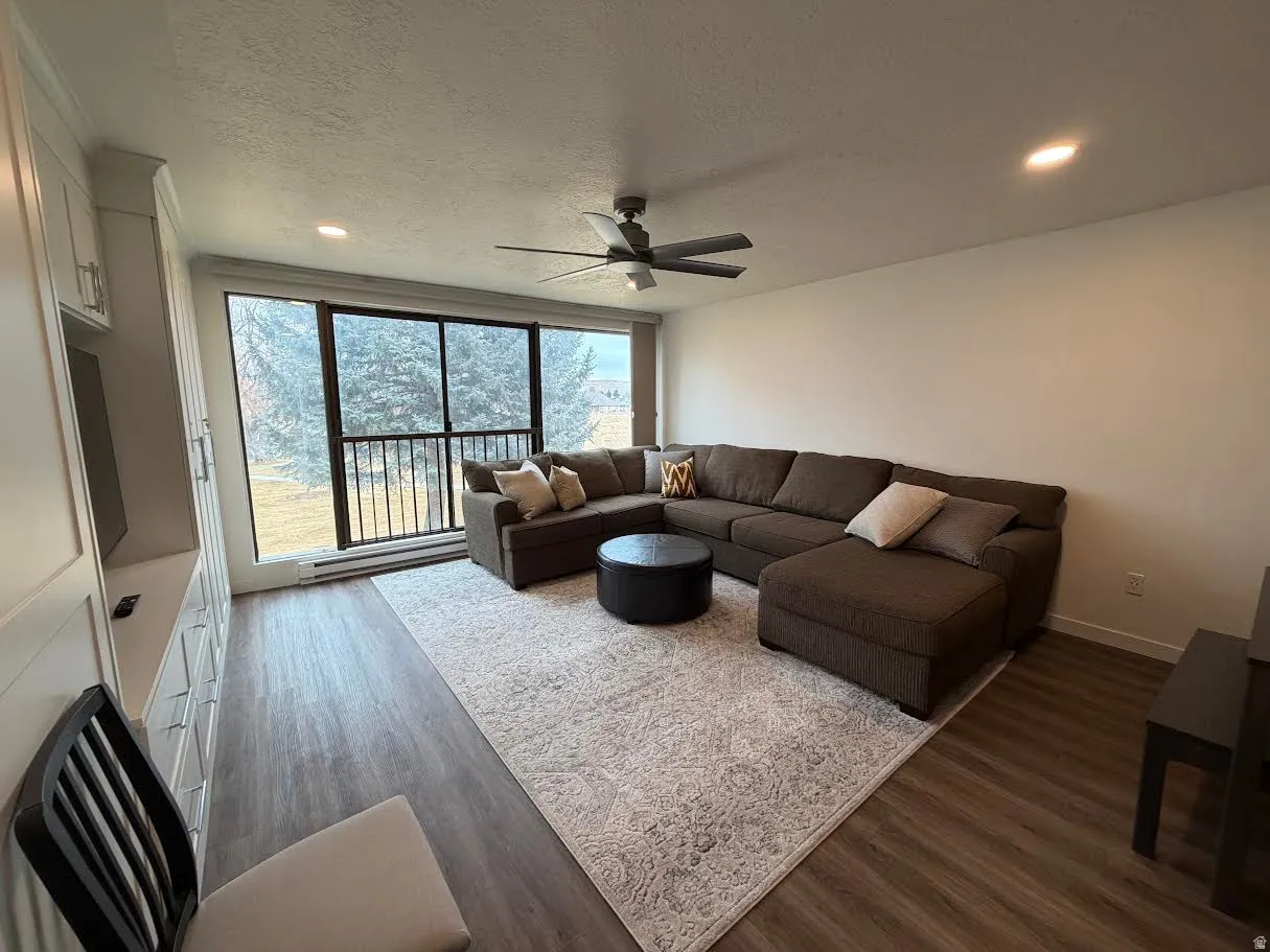 Living room with dark wood-style floors, ceiling fan, a textured ceiling, recessed lighting, and a baseboard radiator