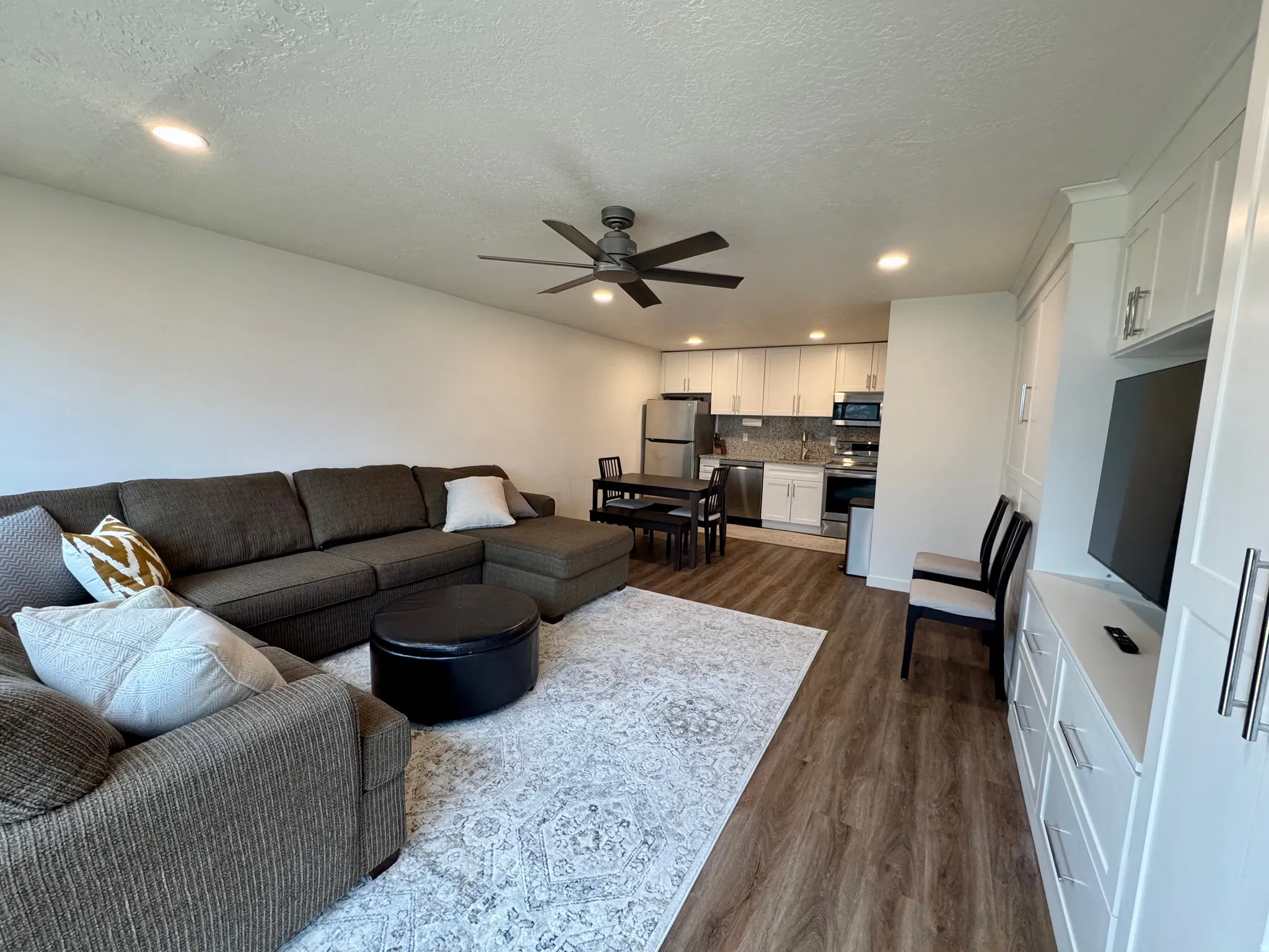 Living room with dark wood-style floors, recessed lighting, ceiling fan, and a textured ceiling