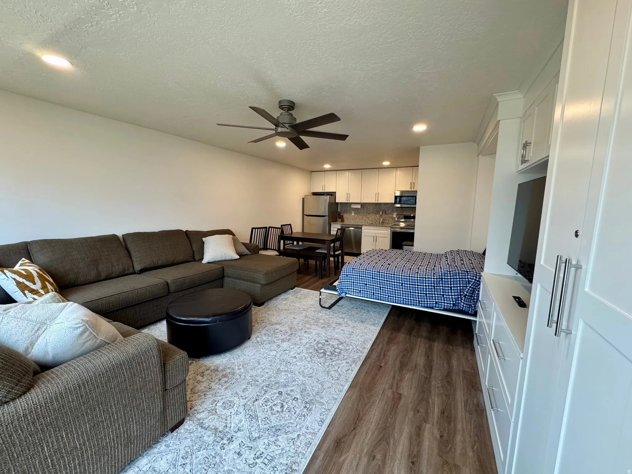 Bedroom featuring dark wood finished floors, freestanding refrigerator, recessed lighting, a textured ceiling, and ceiling fan