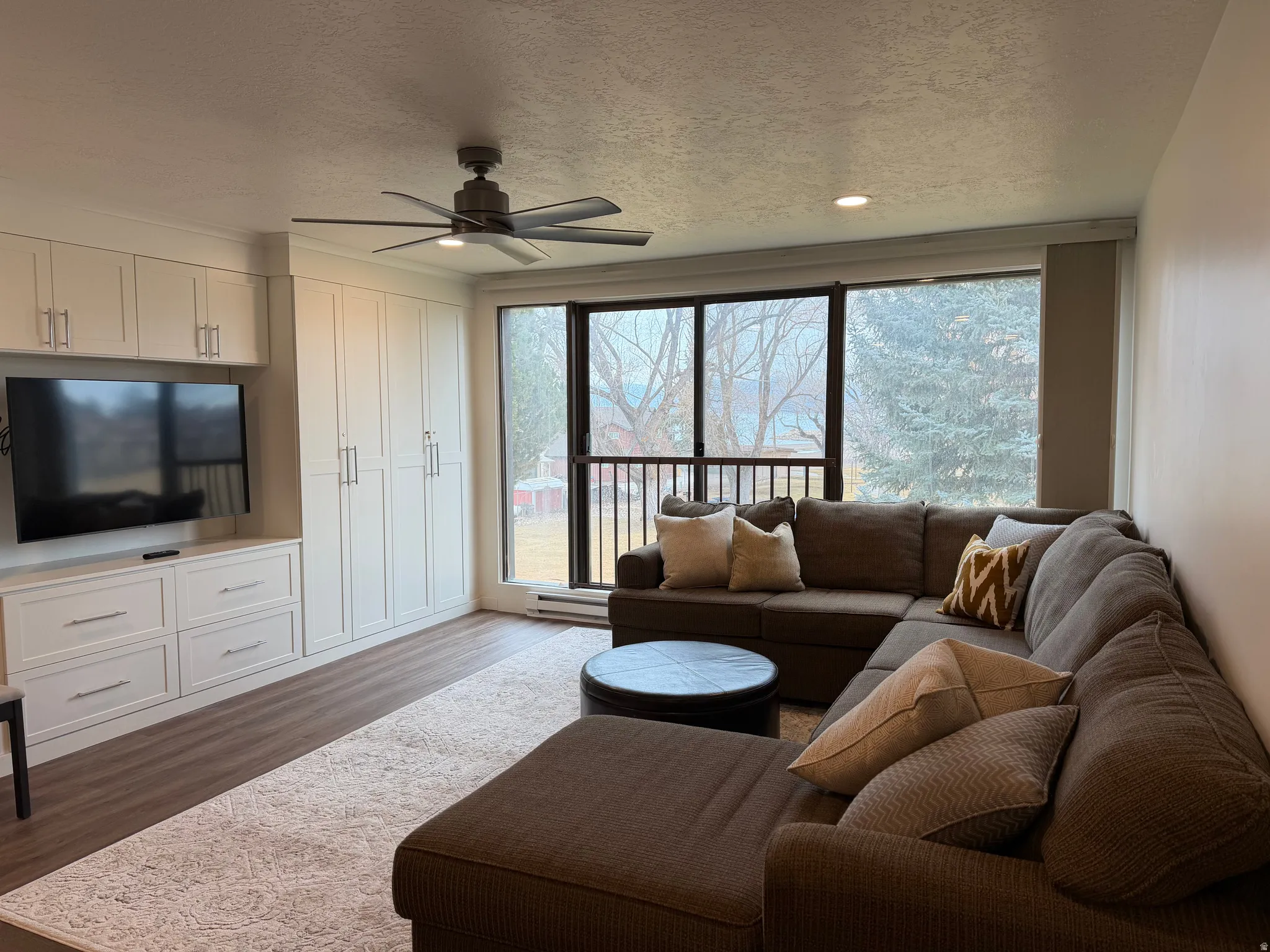 Living area with a textured ceiling, a ceiling fan, dark wood-type flooring, plenty of natural light, and recessed lighting