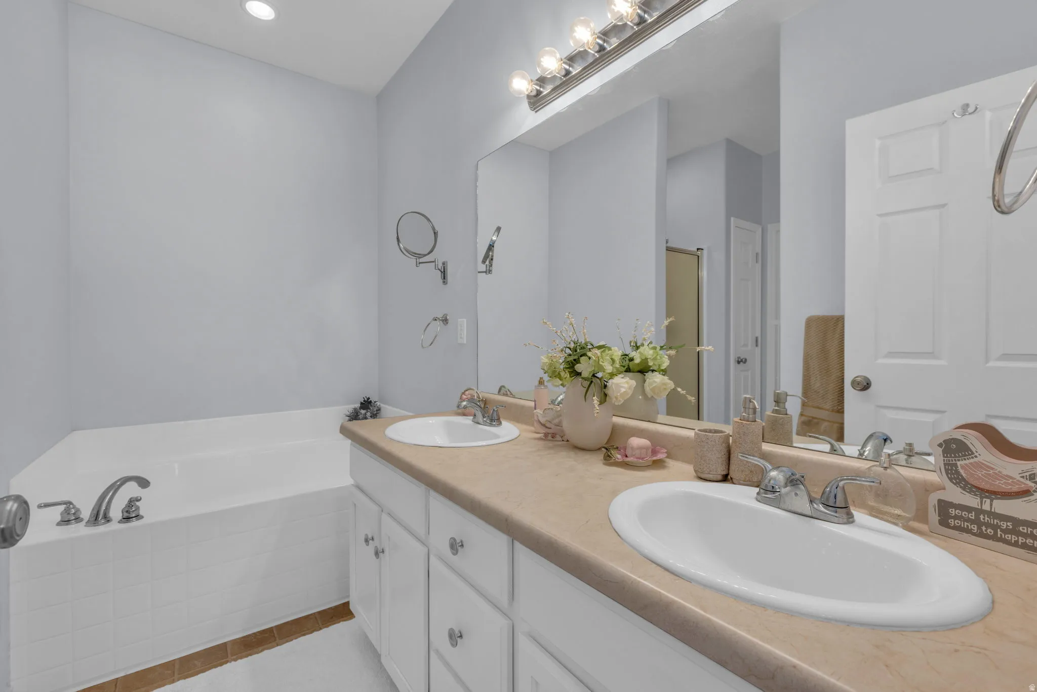 Full bath with a garden tub, double vanity, and light tile patterned floors