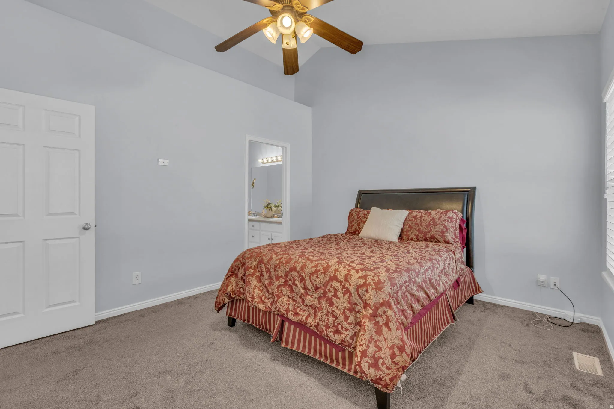 Bedroom featuring lofted ceiling, light carpet, ceiling fan, and connected bathroom