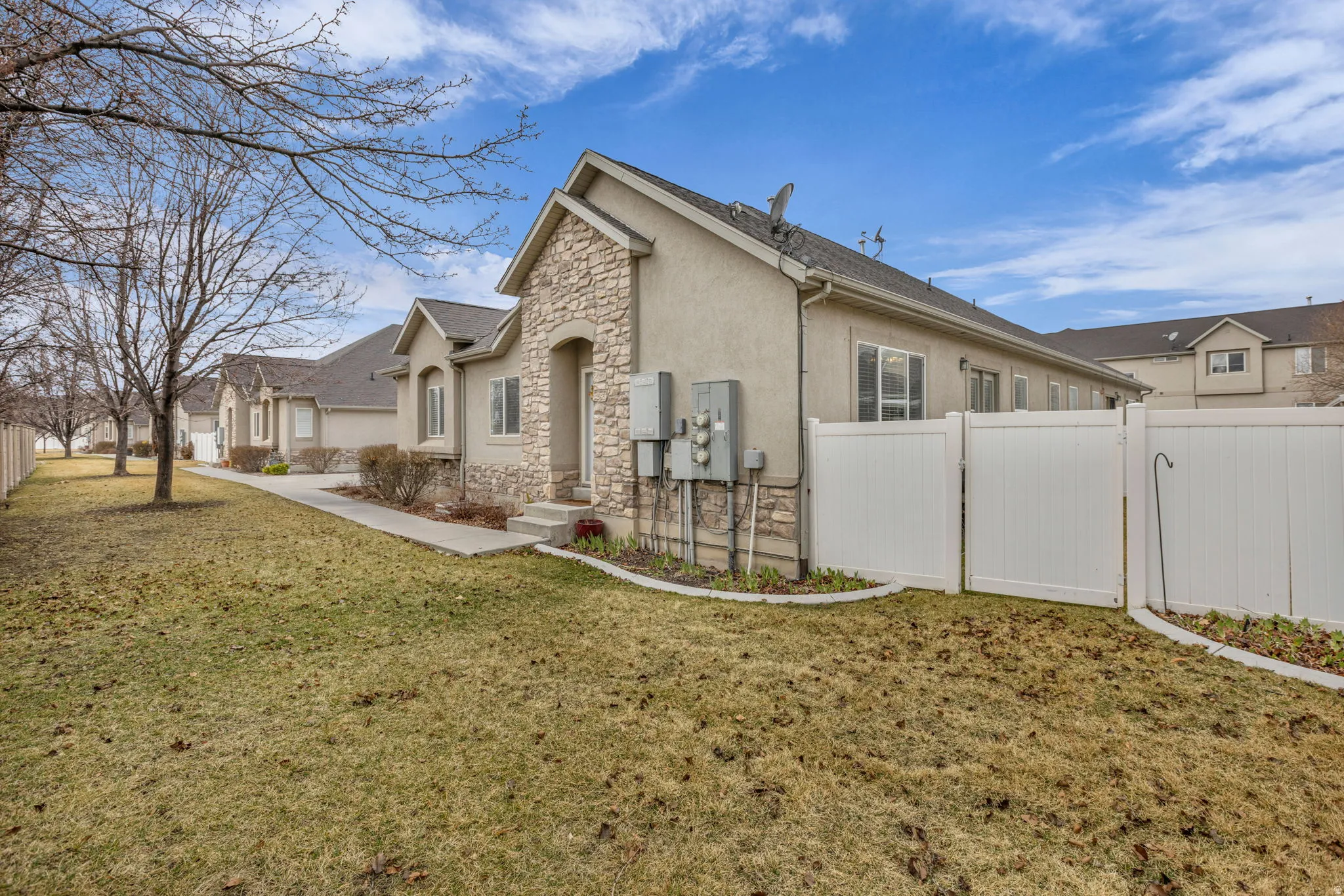 View of home's exterior with stucco siding, stone siding, and a gate