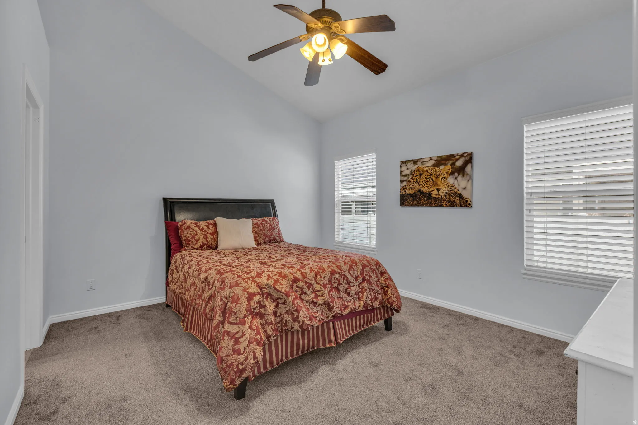 Carpeted bedroom with vaulted ceiling and ceiling fan