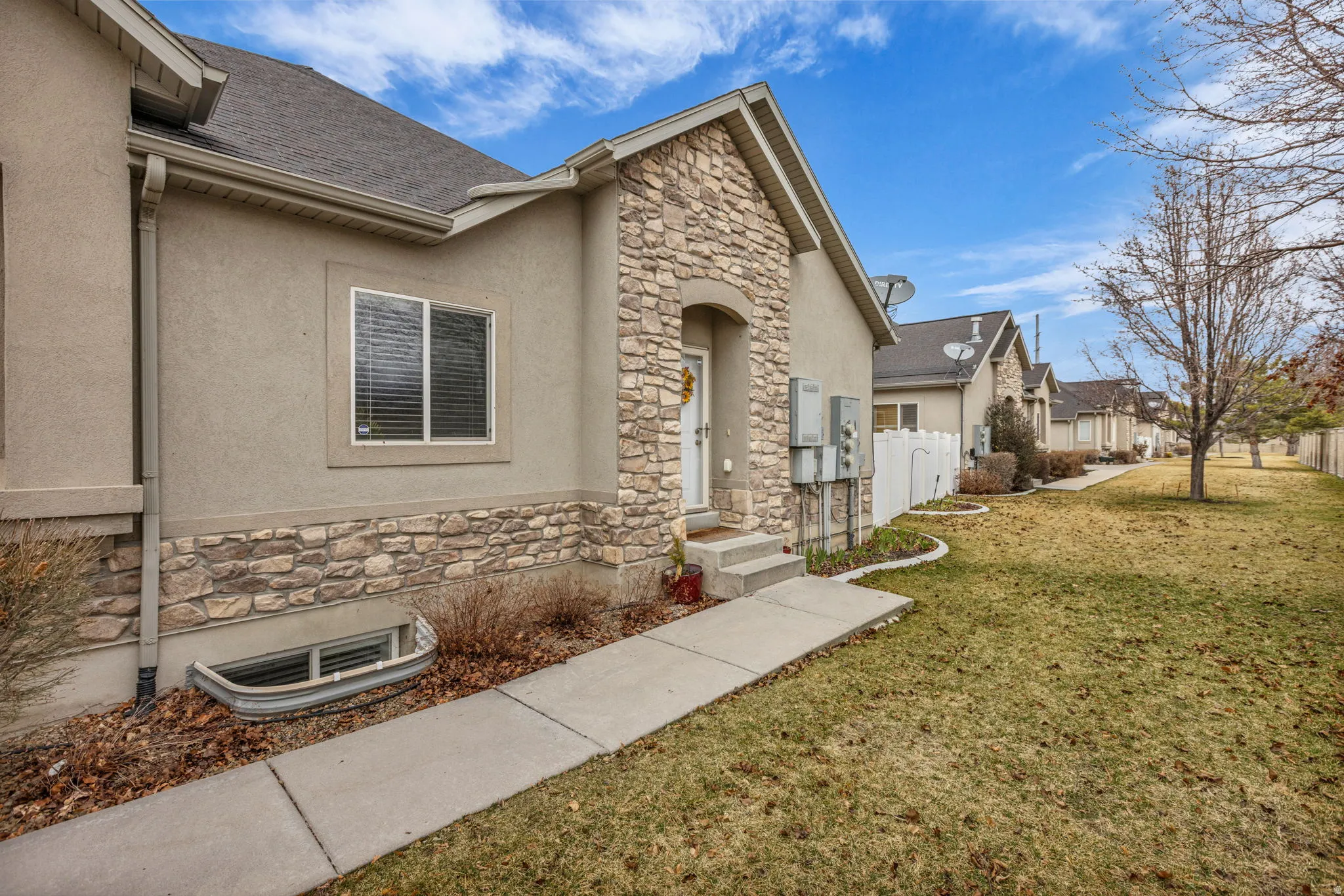 Doorway to property featuring stone siding, stucco siding, and roof with shingles