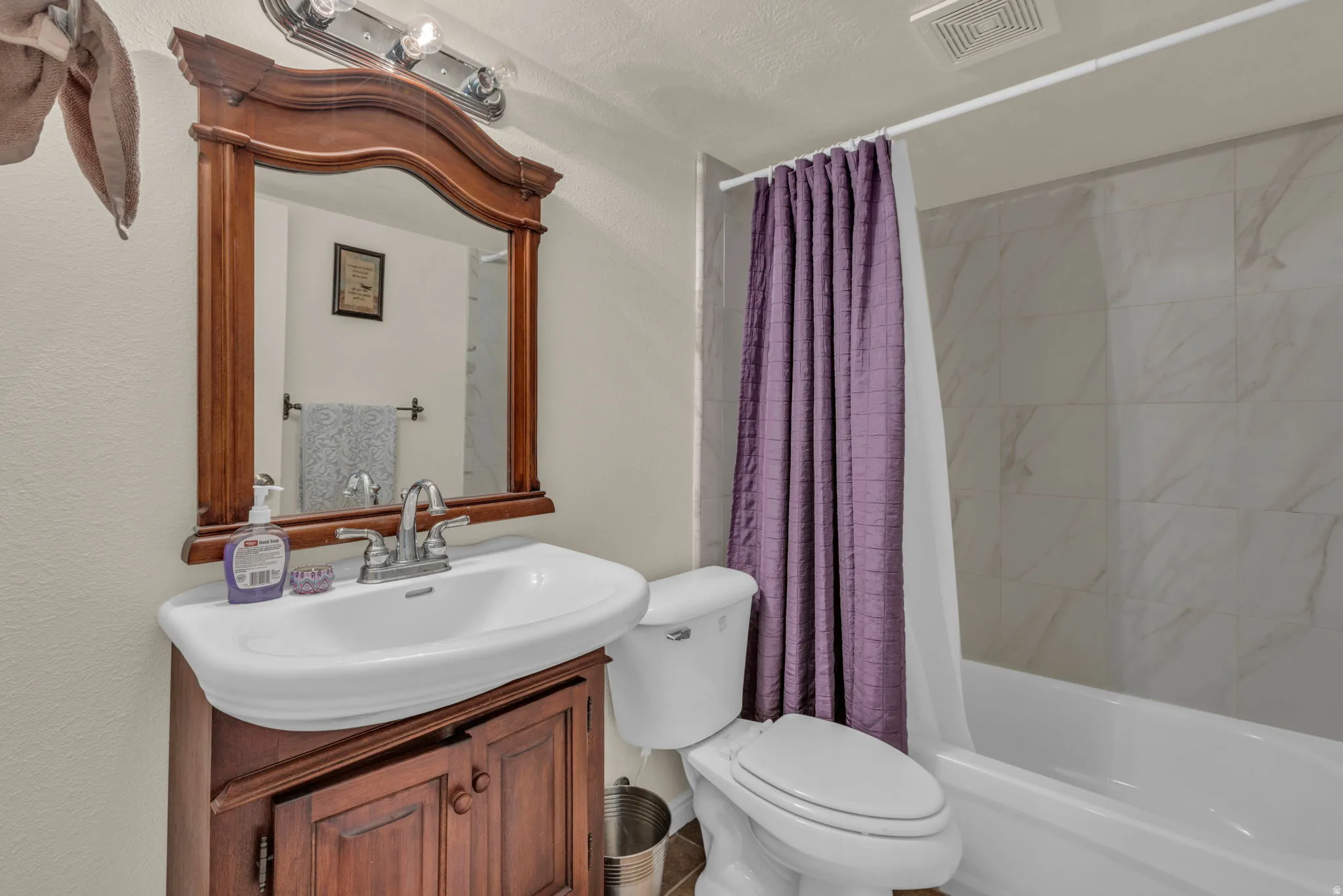 Bathroom featuring vanity and shower / bathtub combination with curtain