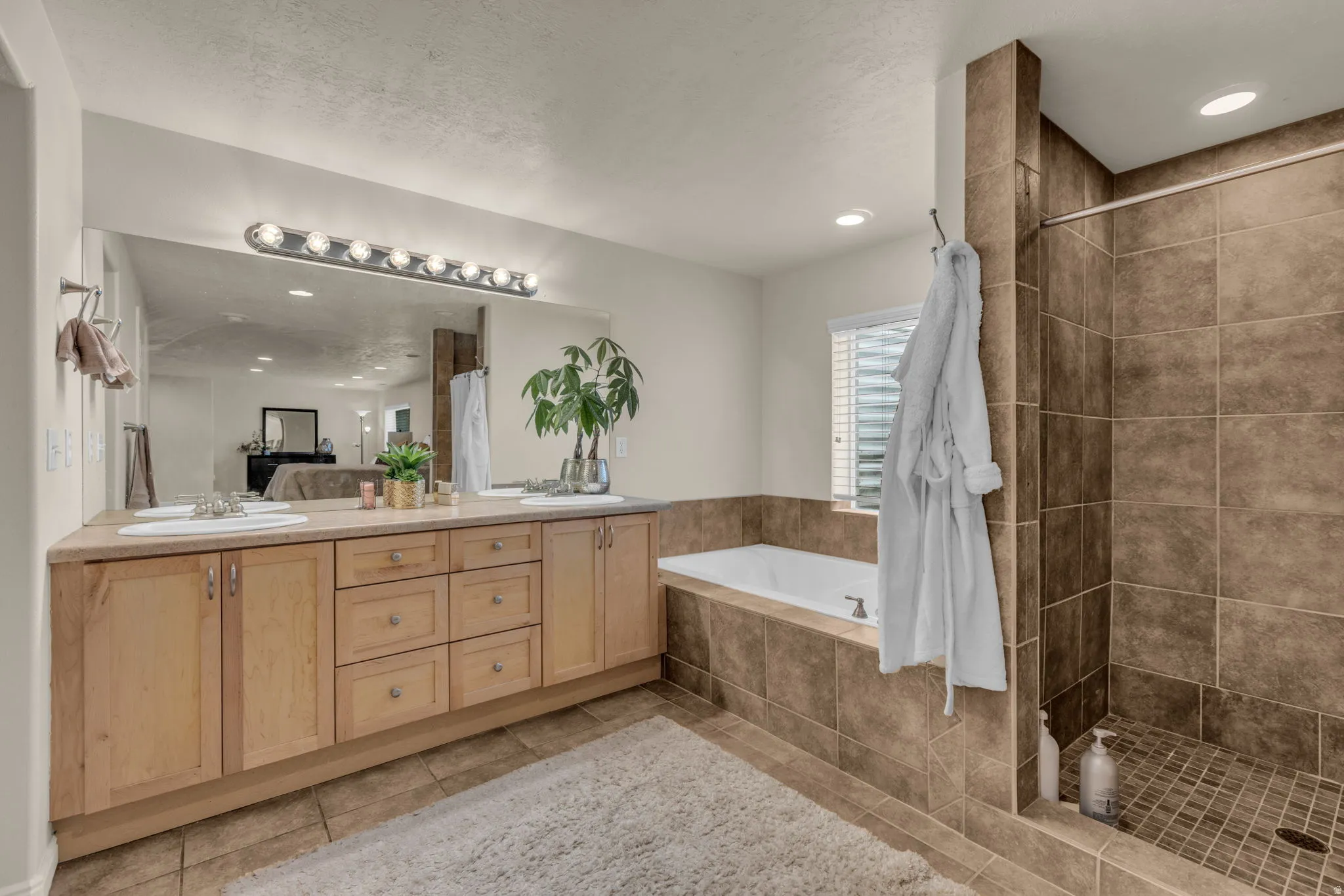 Bathroom featuring double vanity, a bath, a shower stall, recessed lighting, and light tile patterned floors