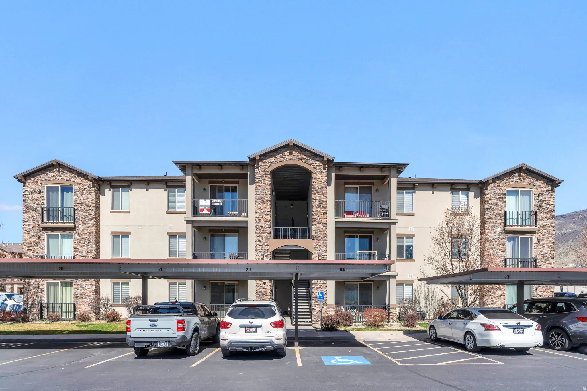 View of apartment building / complex with covered parking and stairs