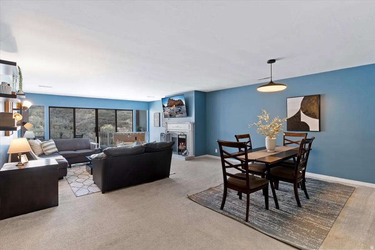 Dining room featuring a warm lit fireplace and light colored carpet
