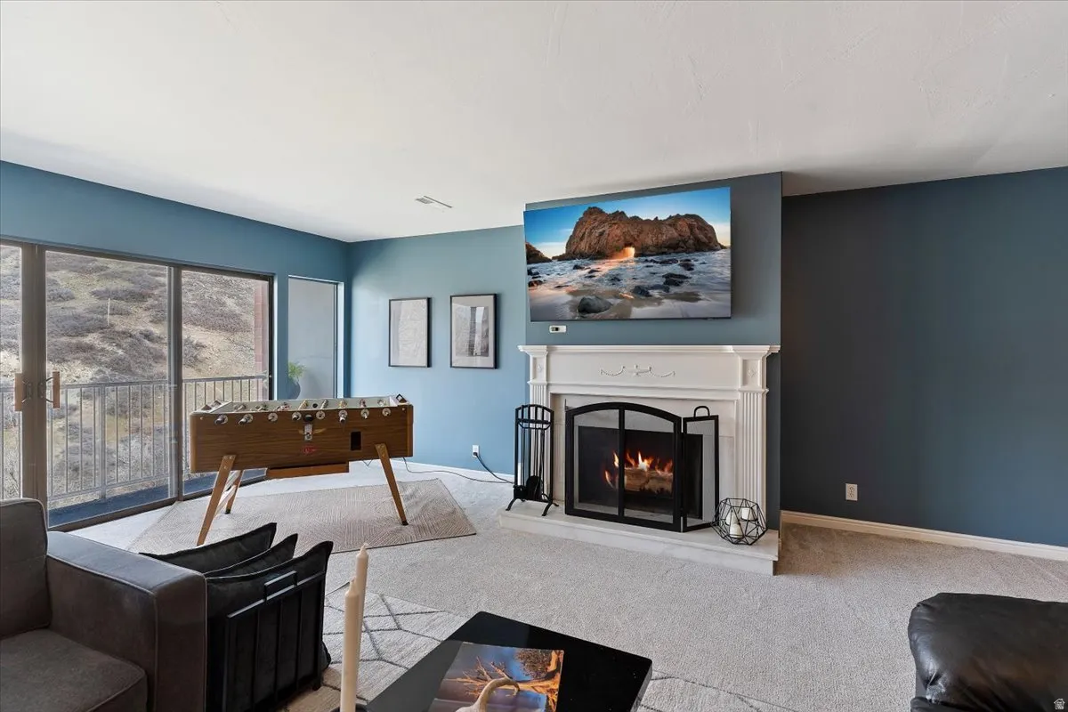 Living area featuring carpet floors and a warm lit fireplace