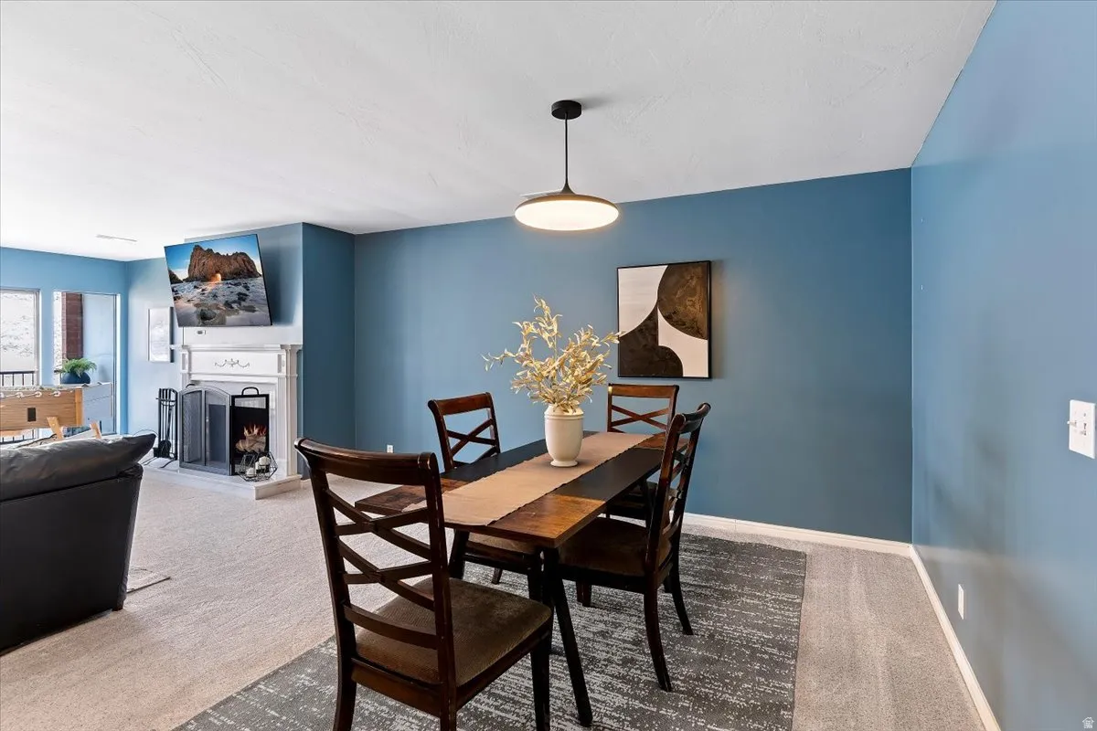 Dining space featuring light carpet and a lit fireplace