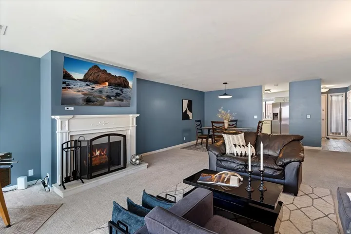 Living area with light carpet and a warm lit fireplace