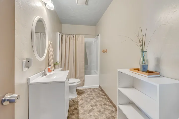 Bathroom featuring vanity, shower / tub combo, a textured ceiling, and stone finish flooring