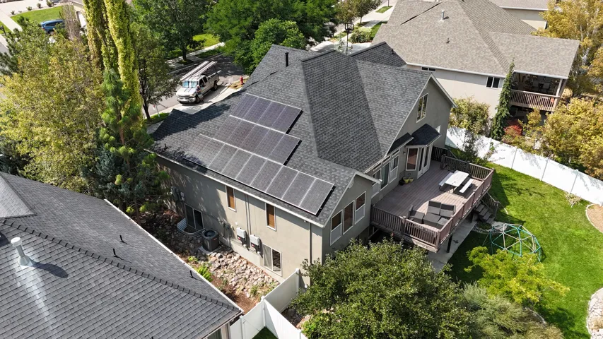 Exterior featuring a neutral-toned facade, multiple solar panels, a multi-level deck, and a manicured lawn