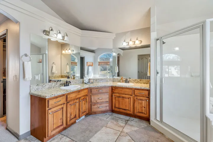 Bathroom with double vanity, a shower stall, and vaulted ceiling