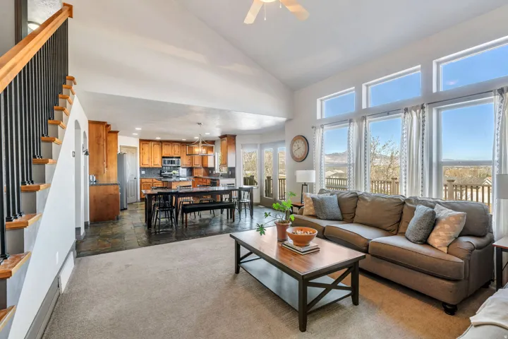 Living area featuring stone tile flooring, a ceiling fan, recessed lighting, vaulted ceiling, and dark carpet