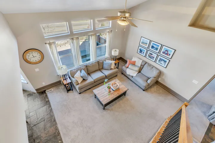 Living room with vaulted ceiling, ceiling fan, and carpet floors