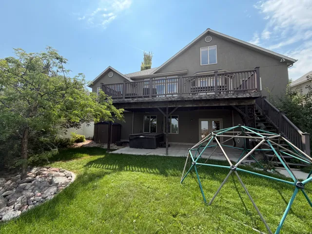 Multi-level outdoor living space featuring a raised deck with railings, a lower-level concrete patio, and exterior stairs