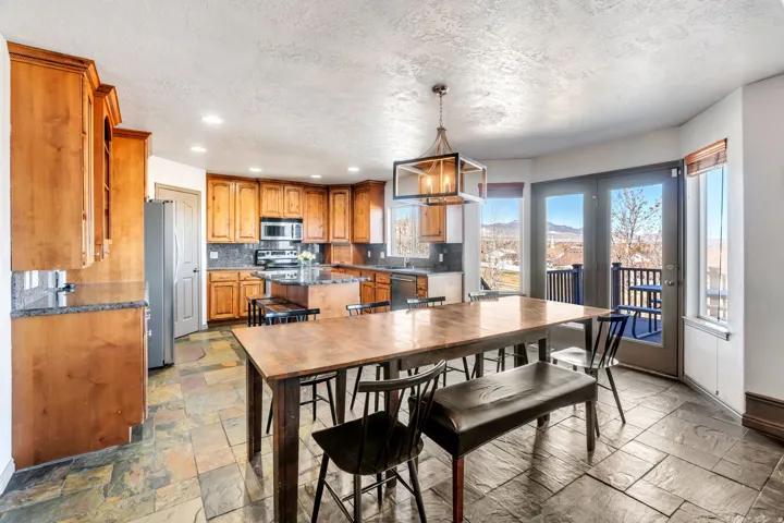 Dining space featuring a chandelier, stone tile floors, a mountain view, and a textured ceiling