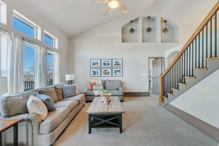 Carpeted living area featuring vaulted ceiling and ceiling fan