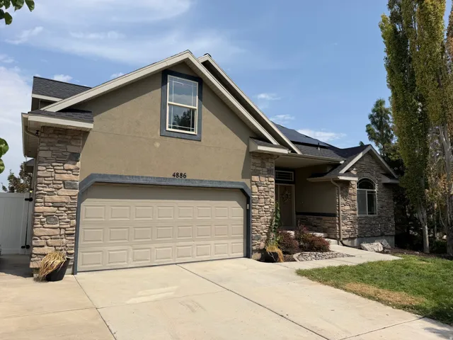 Two-story stucco and stone-faced exterior with an attached garage and concrete driveway