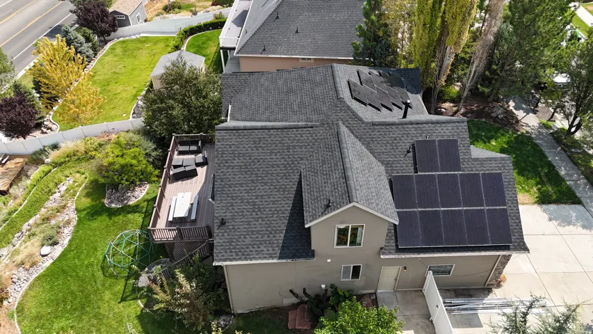 Multi-level exterior with a gray-toned facade, dark shingle roofing, and multiple solar panels