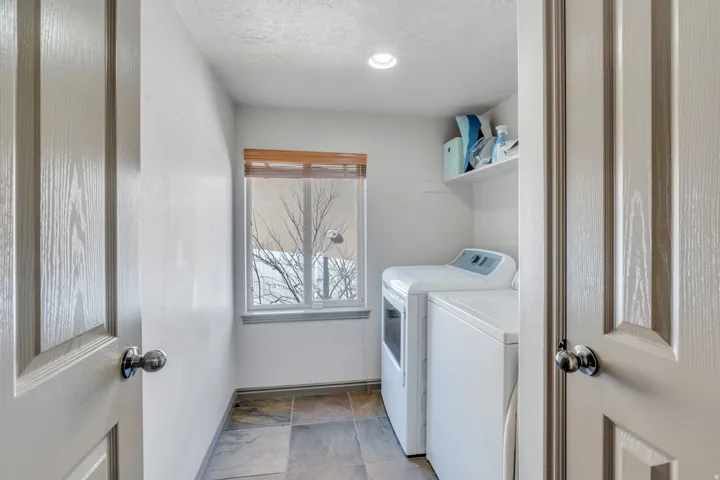 Laundry area with independent washer and dryer, light stone finish floors, and a textured ceiling