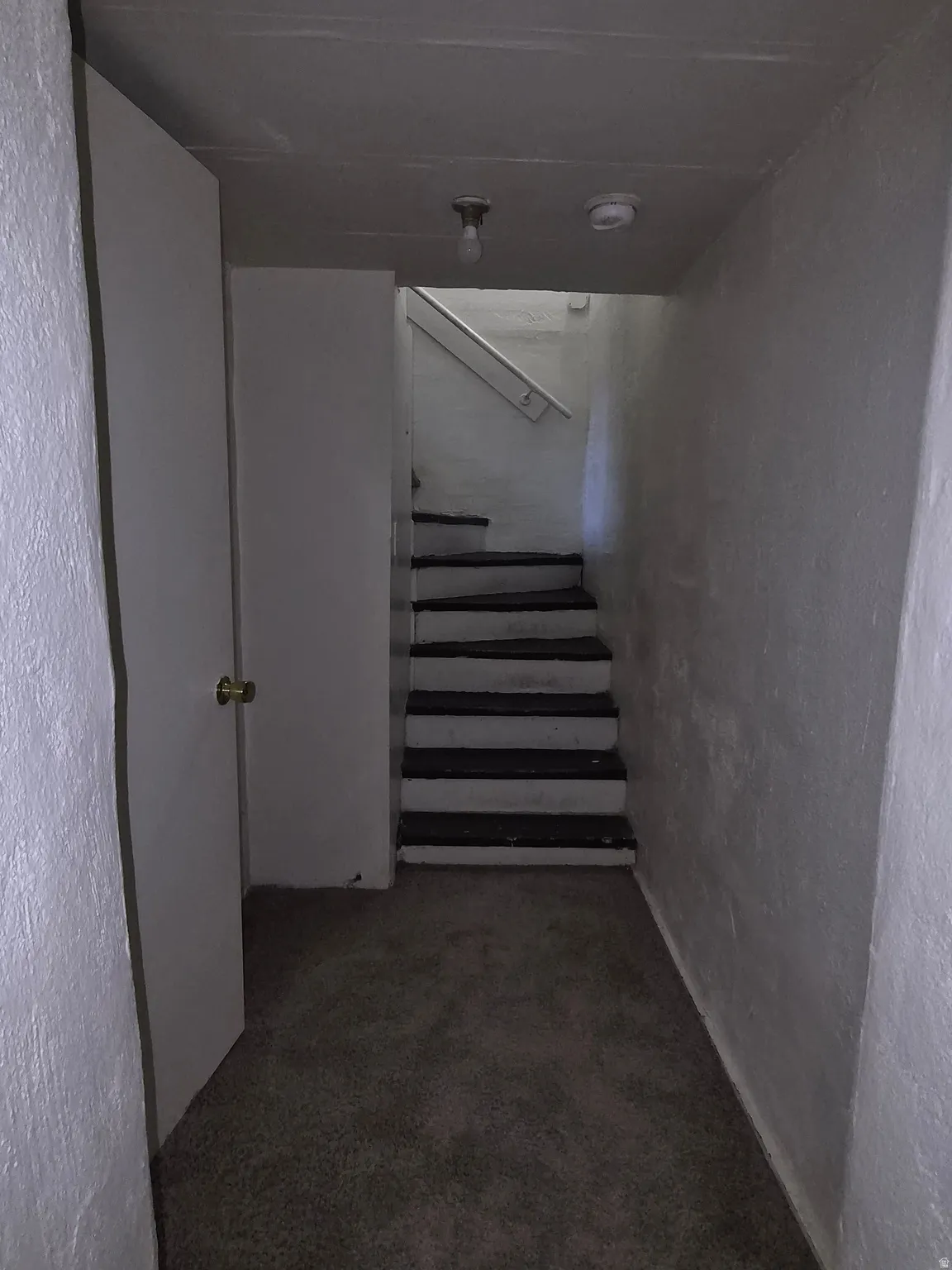 Stairs featuring a textured wall and carpet