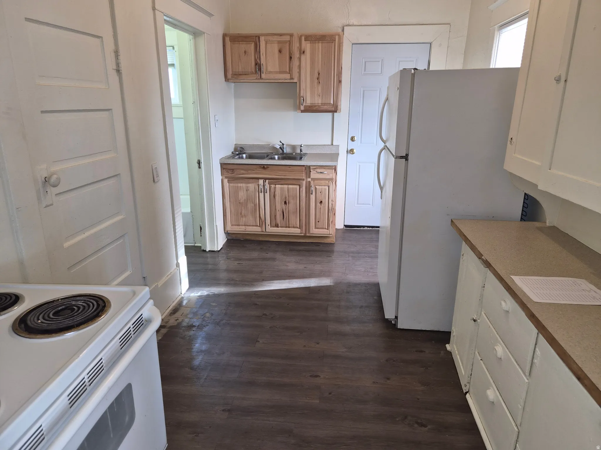 Kitchen featuring white appliances, dark wood-style floors, and light countertops