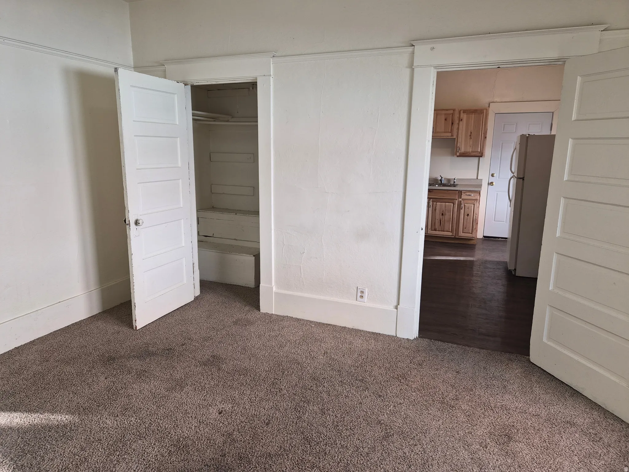 Unfurnished bedroom with dark colored carpet and freestanding refrigerator