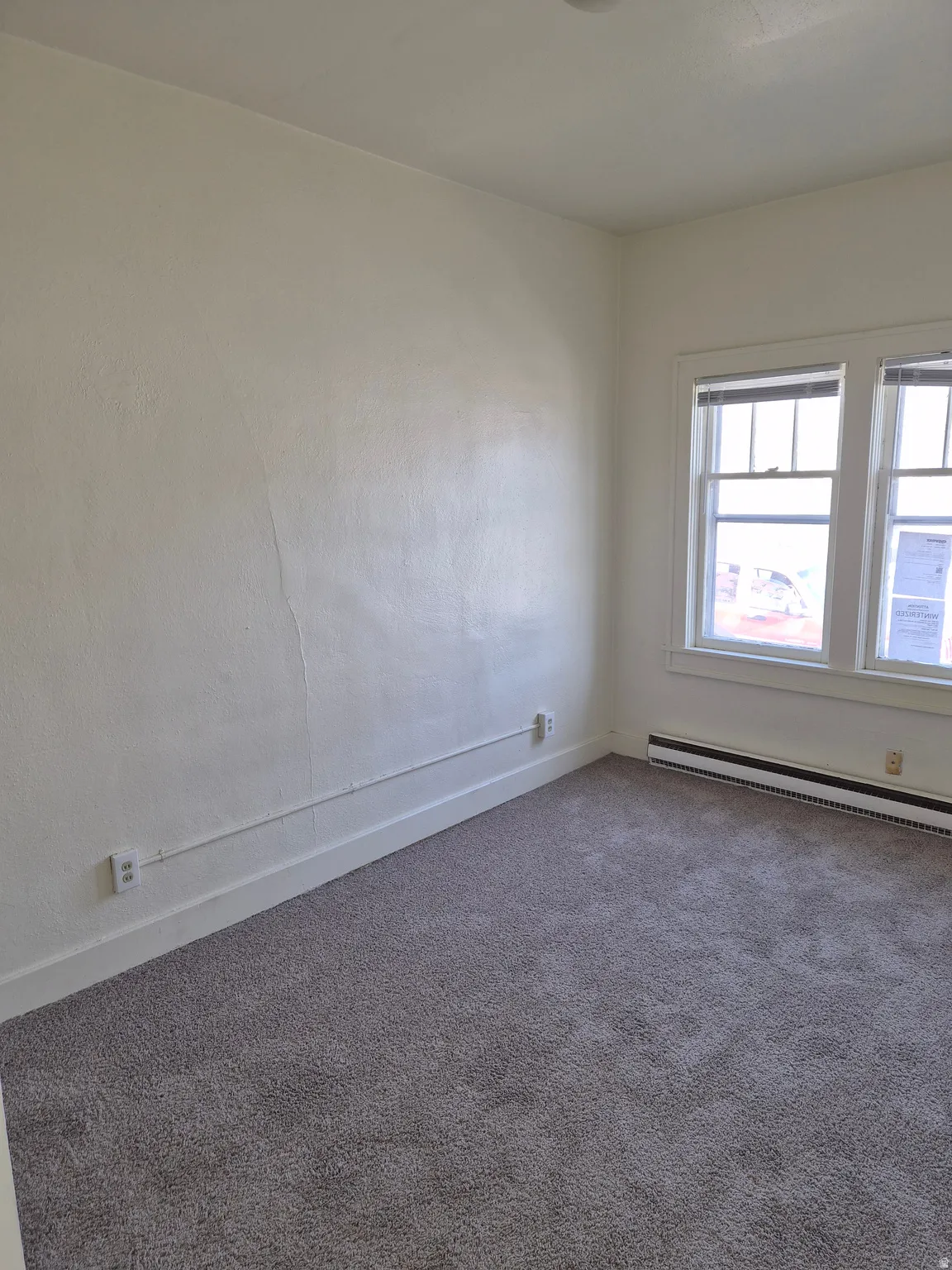 Carpeted empty room with baseboards and a baseboard radiator