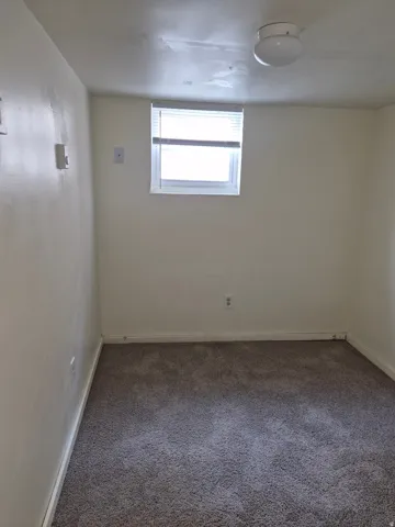 Unfurnished room with dark colored carpet and baseboards