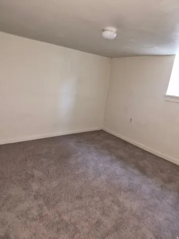 Carpeted spare room featuring baseboards