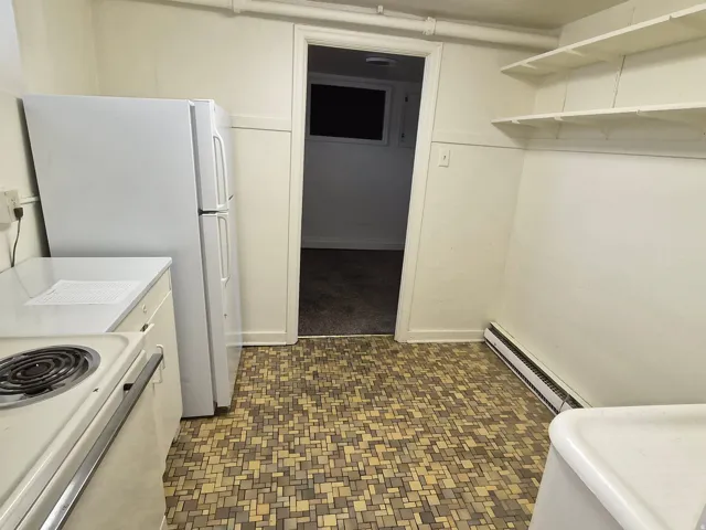 Kitchen with white range with electric cooktop, baseboard heating, dark floors, and light countertops