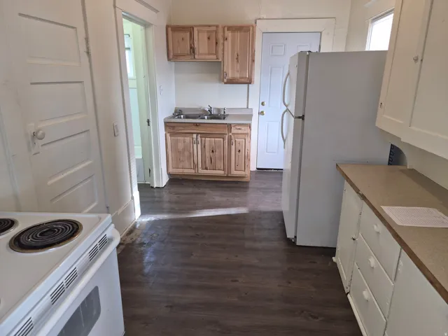 Kitchen featuring white appliances, dark wood-style floors, and light countertops