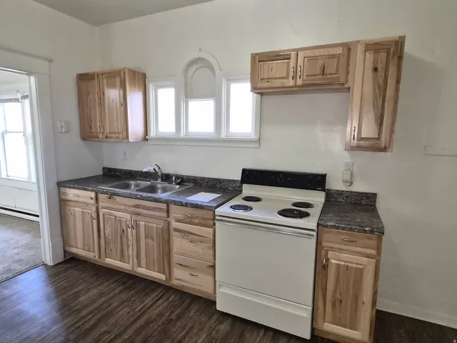 Kitchen featuring dark countertops, white electric stove, dark wood finished floors, and a baseboard radiator