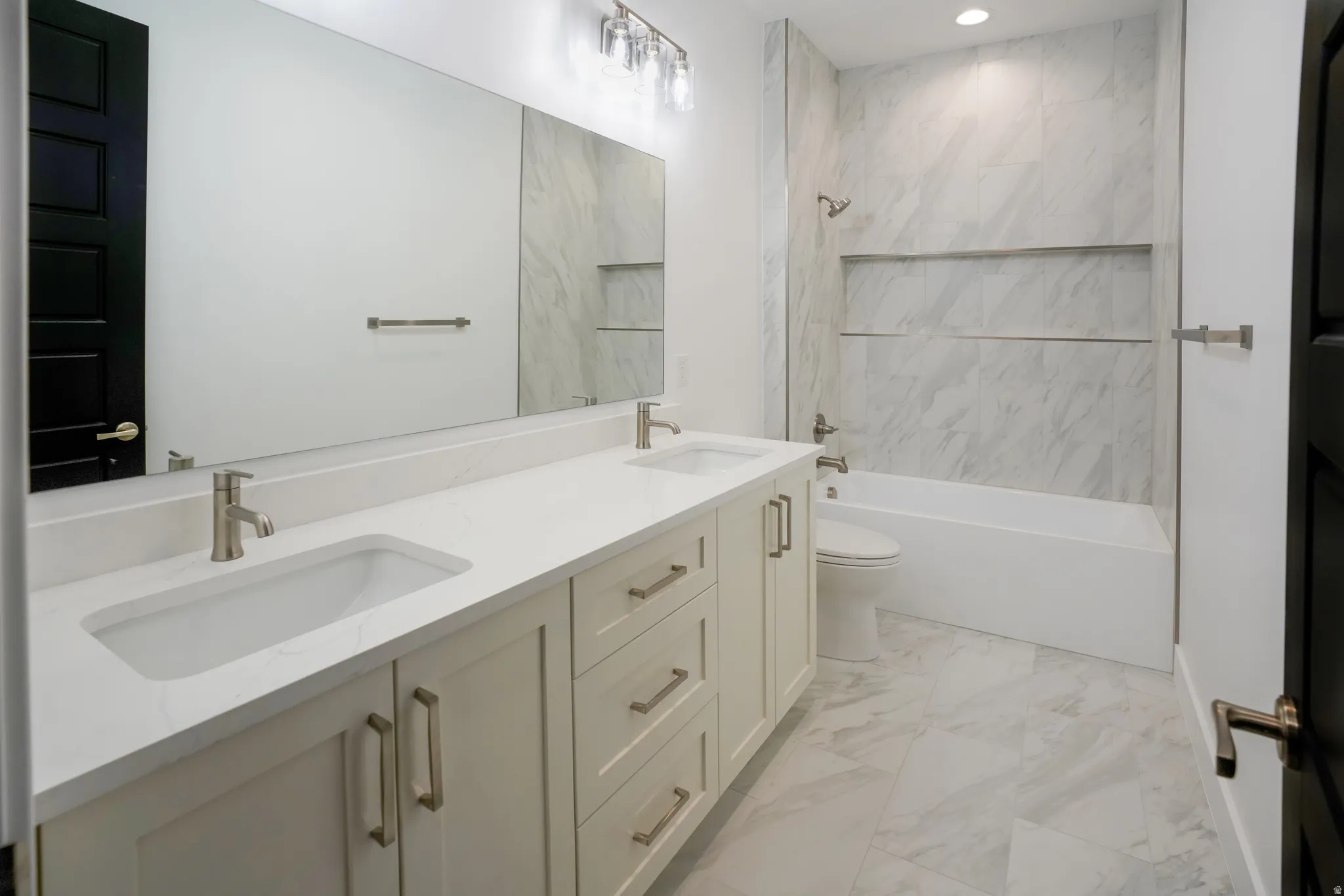 Bathroom with double vanity, light marble finish flooring, and  shower combination